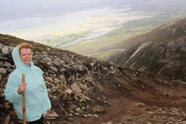 woman on top of mountain travel to Ireland on a budget