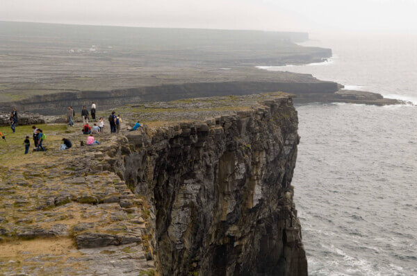 people standing on a cliff overlooking ocean
