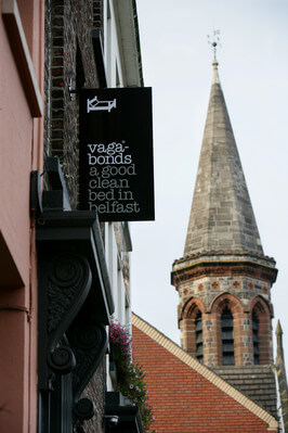 a sign on a building with a church spire in background 24 hours in Belfast