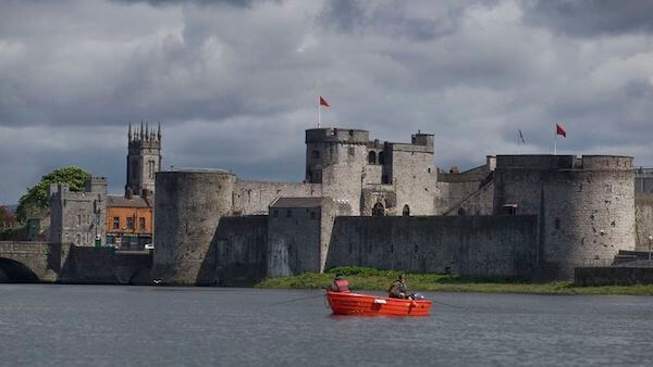 a red boat in the water outside a castle exploring Viking history