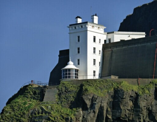 a white building on a cliff Ireland's coolest lighthouses