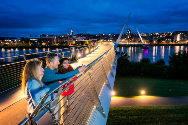 people standing on a bridge at night Derry Girls tour