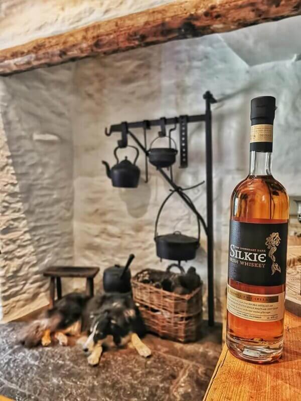 a whiskey bottle on a table and a dog in the corner 10 undiscovered whiskey distilleries in Ireland