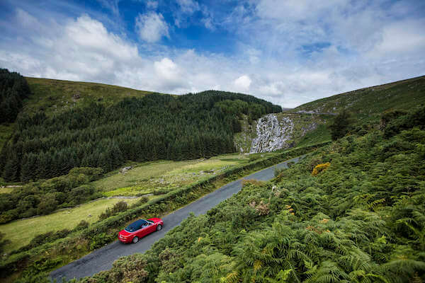 a red car on the road 30 ways to save your trip to Ireland