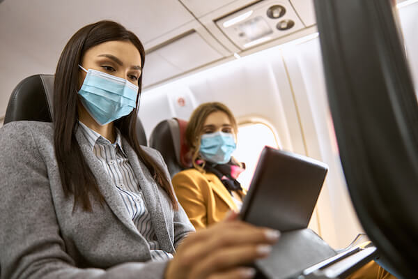 women wearing masks on a plane travel insurance explained