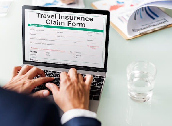 a man typing on a laptop travel insurance explained