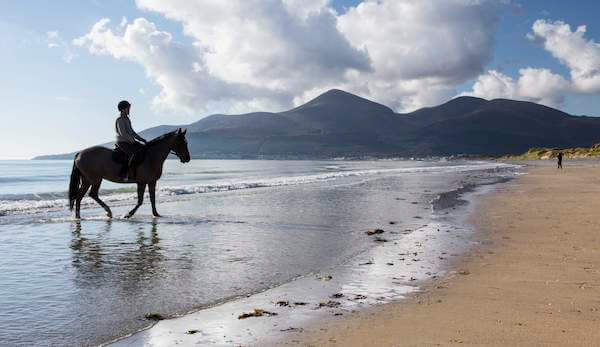 a person on a horse on the beach unique things to do in Ireland'