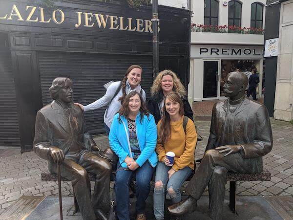 people sitting on a bench near statues Ireland's tourism ambassadors
