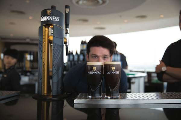 a man looking at two pints of Guinness how to enjoy Ireland's popular tourist attractions