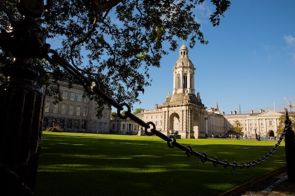 a chain linked fence in front of a building explore Trinity College