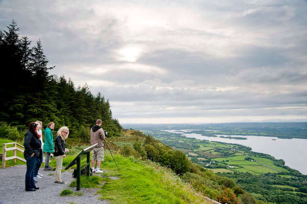 people reading a sign at the top of a hill plan your Ireland 2023 itinerary