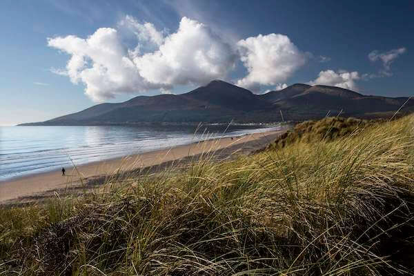 a beach with mountains in the distance from Belfast to the Mourne Mountains