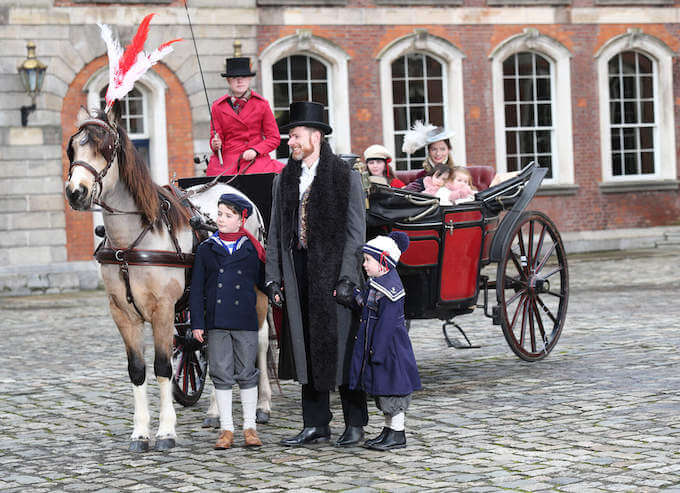 people in a horse and carriage on a cobbled courtyard visiting Dublin for the holidays