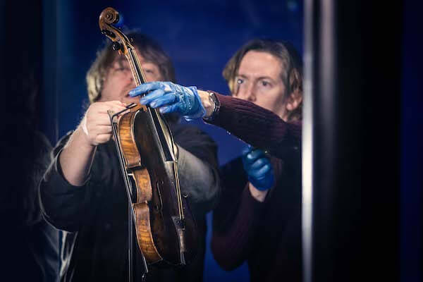 two people holding a violin original Titanic artifacts